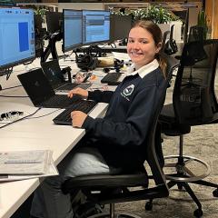 Young woman sitting in front of a computer, smiling at the camera
