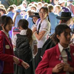 Student surrounded by a group of students, smiling and facing the camera.