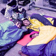 students in sleeping bags on sidewalk
