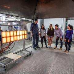 Dr Cristian Maluk inspects fire safety testing equipment with students at the UQ Fire Lab.